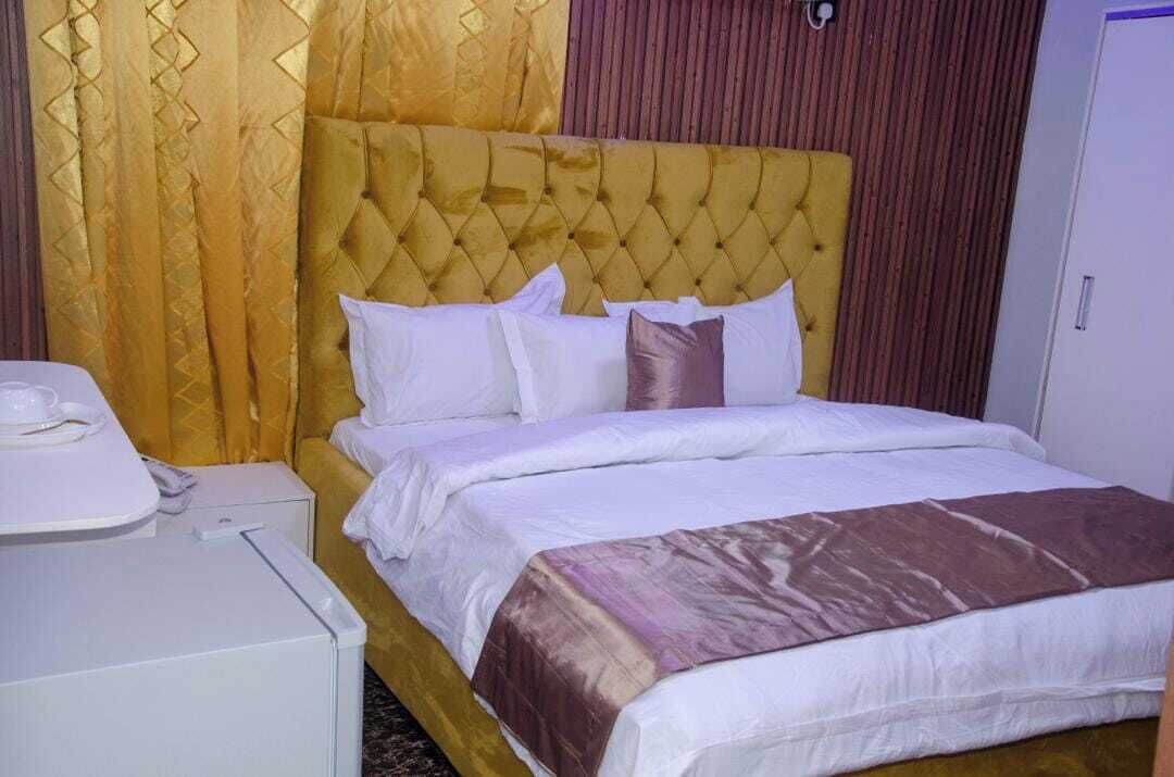 A hotel room with a large bed, a bedside table, and a wardrobe.
