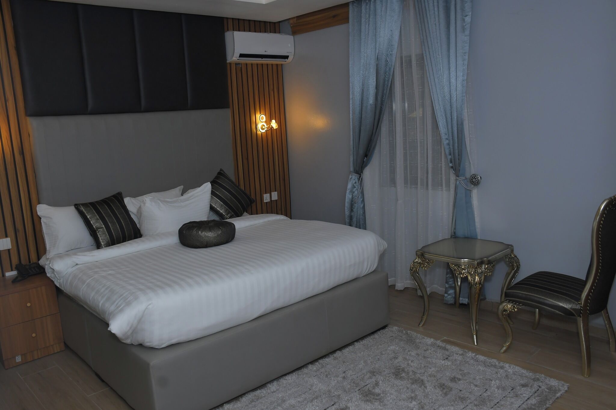 Un dormitorio moderno con una cama grande, una mesita y una silla.