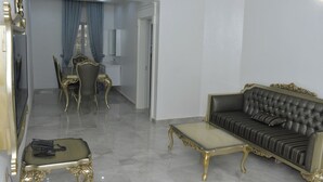 A living room with a black sofa, a glass coffee table, and a dining area with a table and chairs. - Sakura Apartments (Owerri)