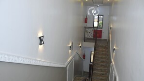 A staircase with a wooden handrail and a metal railing, leading to a landing with a decorative light fixture. - Sakura Apartments (Owerri)