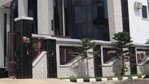 A modern building with a large glass facade, white columns, and a gated entrance. - Sakura Apartments (Owerri)