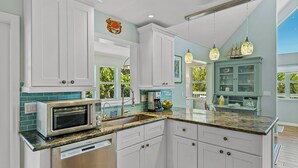 A modern kitchen with white cabinets, a built-in microwave, and a granite countertop.