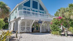 A two-story building with a balcony, a sign reading "Silvernase Cottage," and a surrounding garden with various plants and a palm tree.