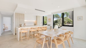Une cuisine moderne dotée d’un îlot central, de chaises en bois et d’une grande fenêtre donnant sur un paysage verdoyant.