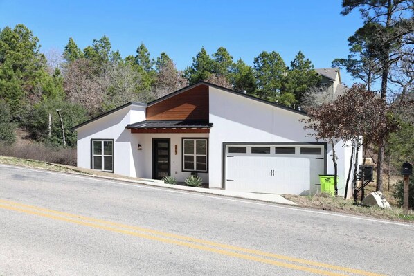 A single-story building with a white exterior, a dark brown roof, and a garage. - Master suite/ Soaking Tub/ Spacious Kitchen (Bastrop)
