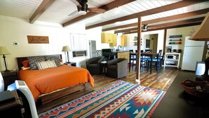 Una habitación con cama, escritorio y zona de cocina.