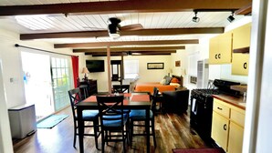 Una sala acogedora con una mesa de comedor, sillas, un sofá y una cocina equipada con armarios y electrodomésticos.