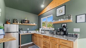 A compact kitchen with wooden cabinets, a built-in microwave, and a coffee bar. - Views! Private Hot tub and Fire Pit! Lux Couple's Retreat (Omaha)