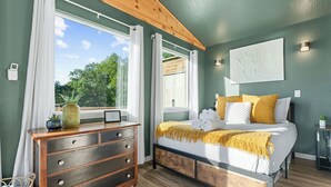 A bedroom with a bed, wooden dresser, and a window with curtains. - Views! Private Hot tub and Fire Pit! Lux Couple's Retreat (Omaha)