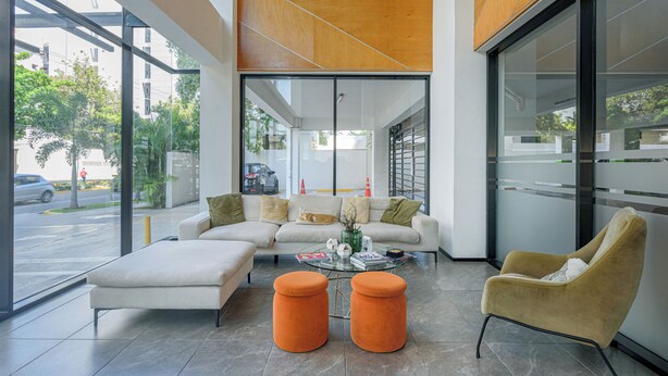 Un interior moderno con un sofá, otomanas y una silla.