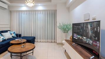 Una sala de estar moderna con un sofá, una mesa de centro y un televisor de pantalla plana mostrando la interfaz de Netflix.