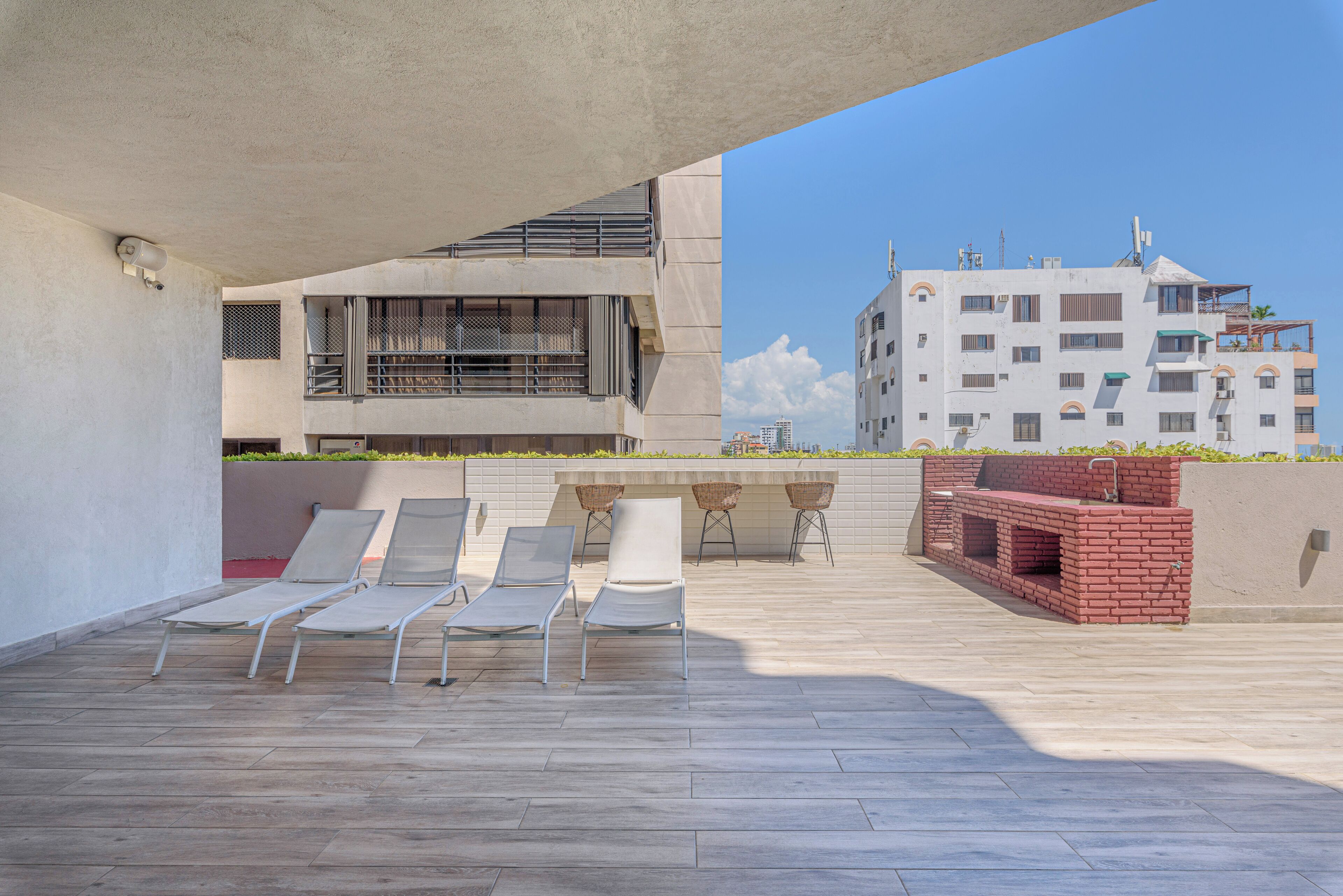 Un área de estar al aire libre con sillones y una parrilla, con vistas a un paisaje urbano.