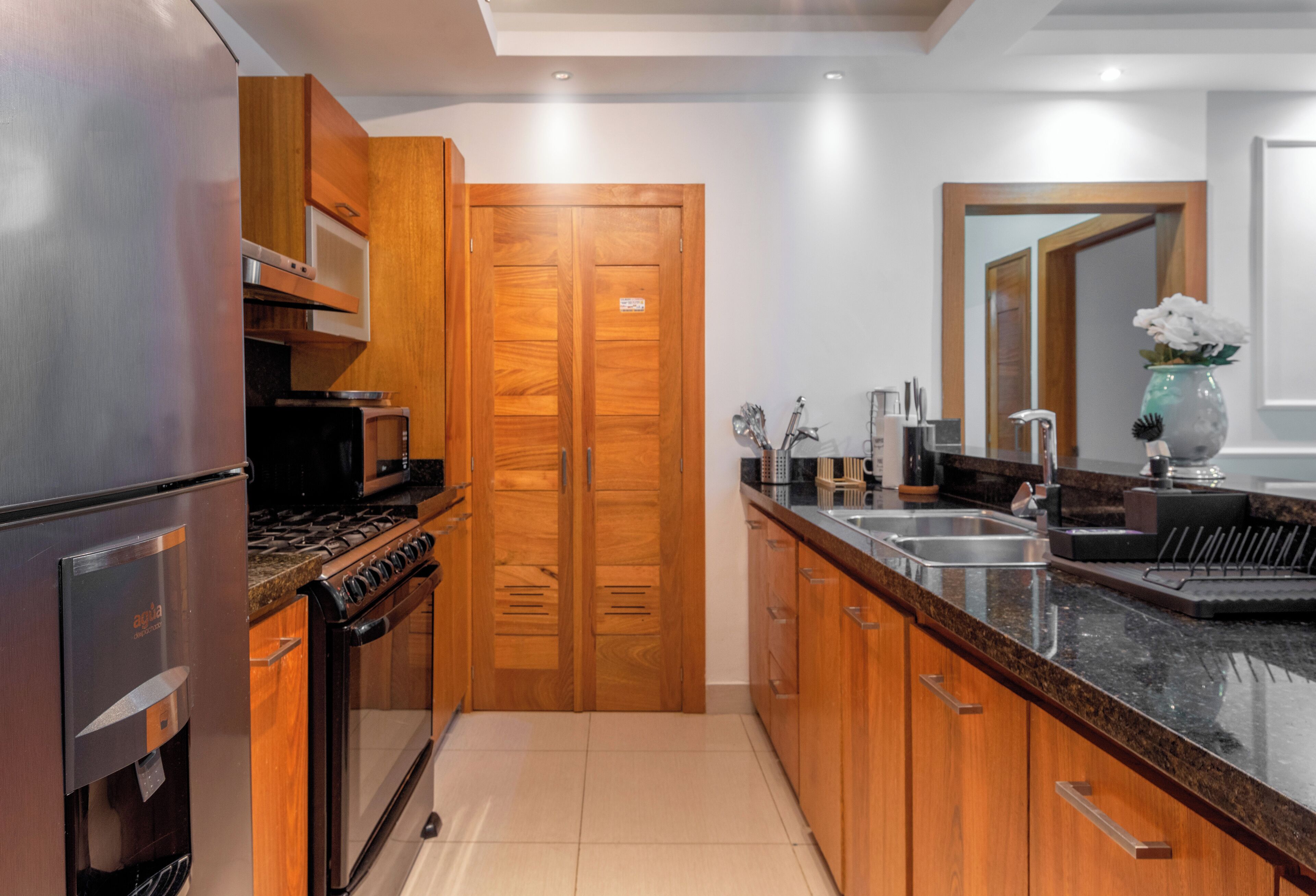 Eine moderne Küche mit Edelstahlgeräten, Holzschränken und einer Granit Arbeitsplatte.