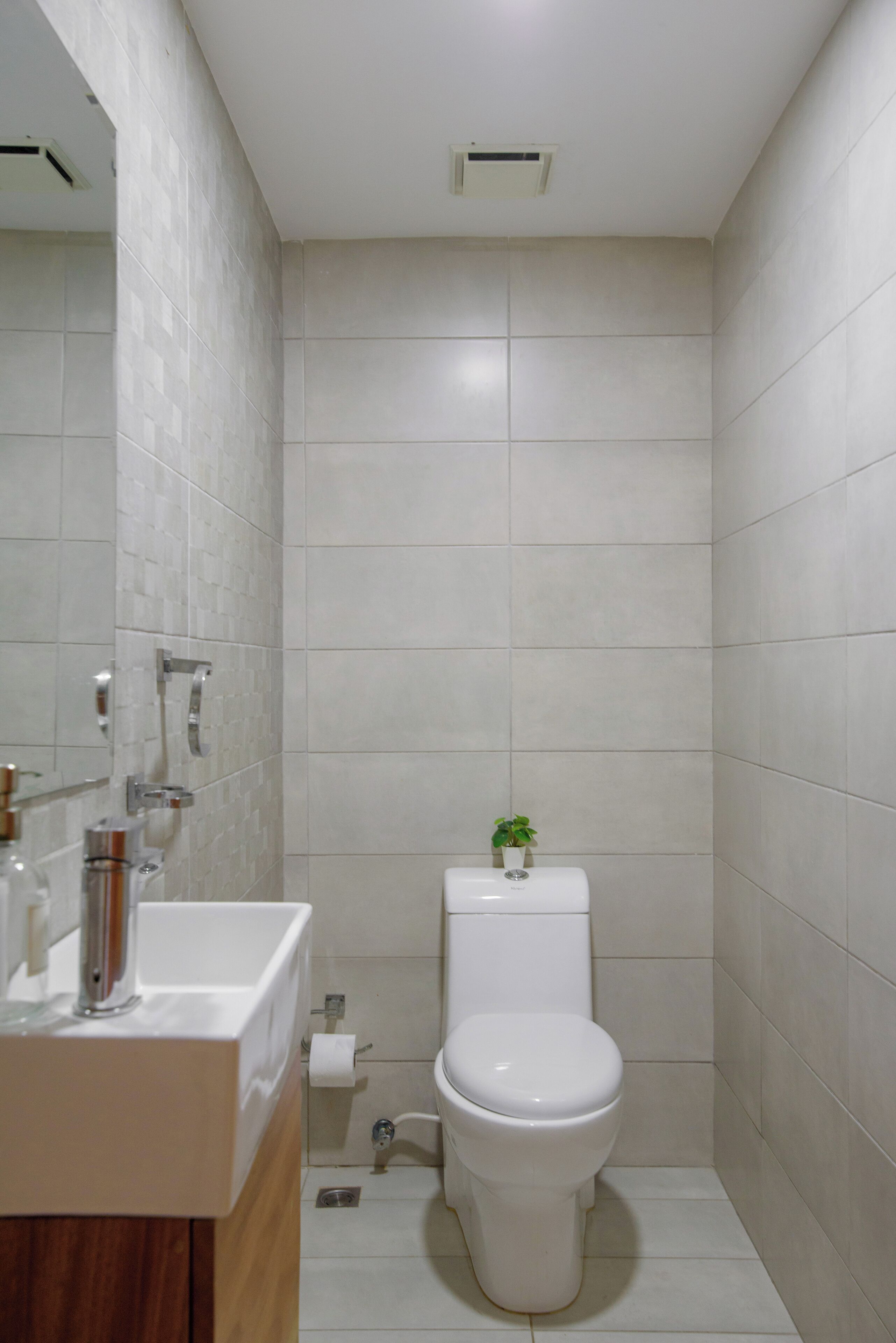 A bathroom with a toilet, sink, and mirror.