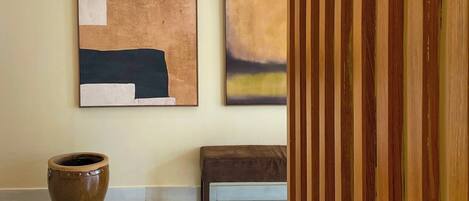 A modern interior with two abstract paintings on the wall, a large ceramic pot, and a bench.