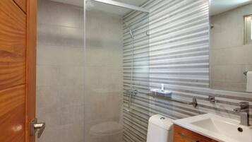 Une salle de bain moderne avec une douche à parois de verre, des toilettes blanches et un meuble-lavabo en bois avec un évier.