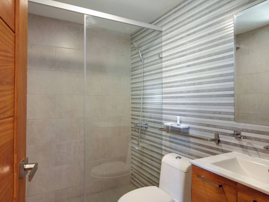 Une salle de bain moderne avec une douche à parois de verre, des toilettes blanches et un meuble-lavabo en bois avec un évier.
