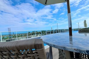 A balcony with a view of the ocean, a metal railing, and a seating area. - Ed. Nixxus Residence (Ipojuca)