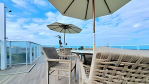 A deck with wicker furniture, a table, and an umbrella. - Ed. Nixxus Residence (Ipojuca)