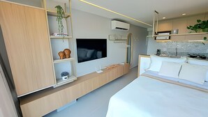 A modern bedroom with a bed, a TV, built-in shelves, and a plant. - Ed. Nixxus Residence (Ipojuca)