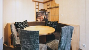 Un rincón comedor acogedor con una mesa redonda de madera rodeada de sillas con cojines y tapicería estampada.