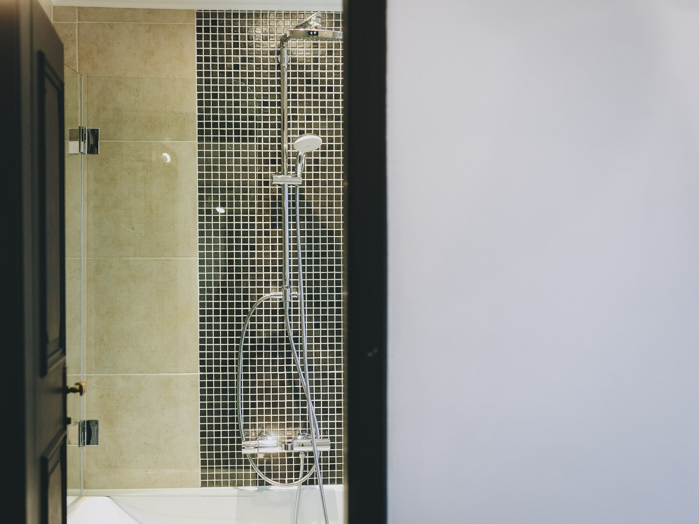 A bathroom with a tiled shower area, a bathtub, and a door.