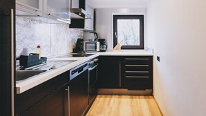 Une cuisine compacte équipée d’un four à micro-ondes, d’une bouilloire et de meubles de rangement modernes.