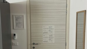 Une porte avec un avis encadré, un thermostat fixé au mur, un interrupteur et une poignée de porte.