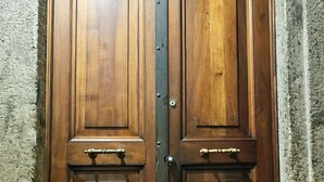 Une porte à deux battants en bois, dotée d’une poignée en métal et d’un trou de serrure, le tout encadré par un cadre en pierre.