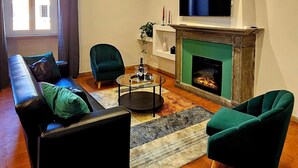 Una sala de estar con chimenea, un sofá, dos sillones y una televisión.
