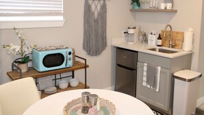 A compact kitchen with a microwave, sink, and storage shelves.