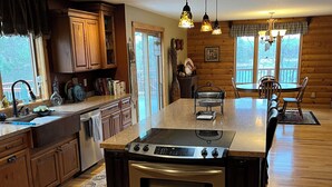 Une cuisine moderne avec des meubles en bois, un îlot central, des appareils en acier inoxydable et des luminaires suspendus.