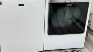 A front-loading washing machine with a control panel and a dryer stacked above it.