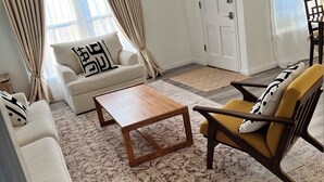 A living room with a sofa, armchair, coffee table, and patterned rug.