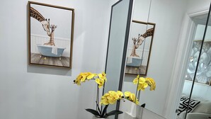 A modern bathroom with a white sink, a large mirror, and a framed picture of giraffes on the wall.