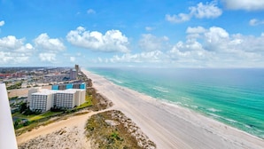 A coastal view with a beach, ocean, and buildings in the background. - Boardwalk 2101 (Panama City Beach)