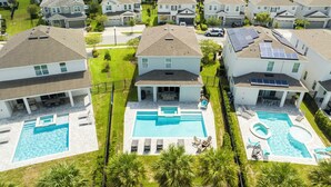 A residential area with three houses, each with a swimming pool and solar panels on the roof.
