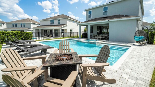 A backyard with a swimming pool, lounge chairs, and a patio table.