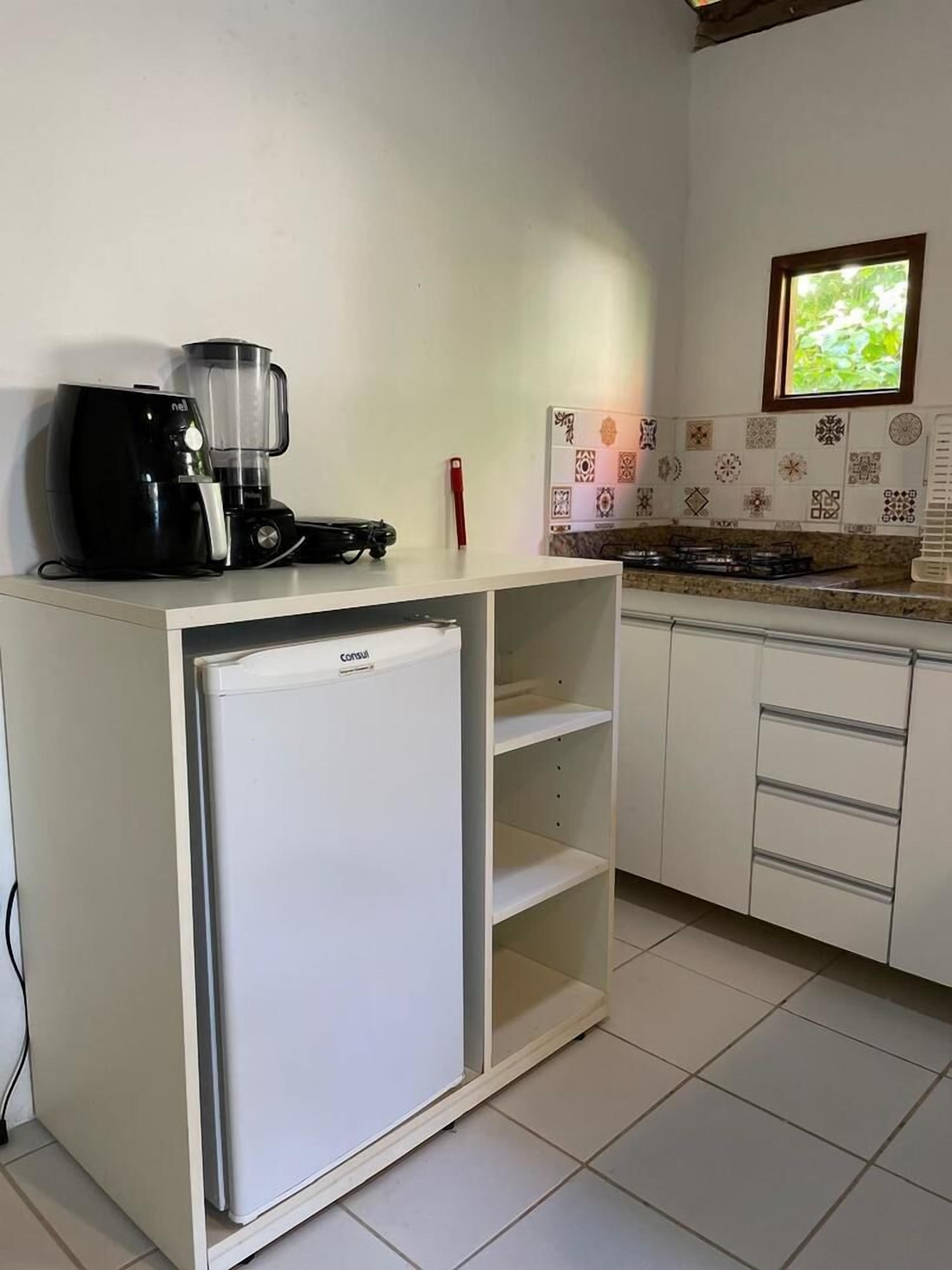 A compact kitchen with a refrigerator, a coffee maker, and a blender on the countertop.