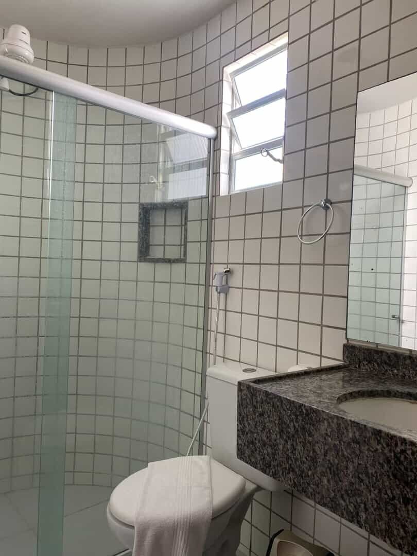 Une salle de bain avec une douche à parois de verre, des toilettes blanches, un lavabo en marbre et un miroir au-dessus du lavabo.