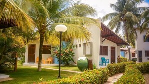 A resort with a white building, palm trees, and a pathway. - Pousada Bangalôs Do Pontal (Japaratinga)
