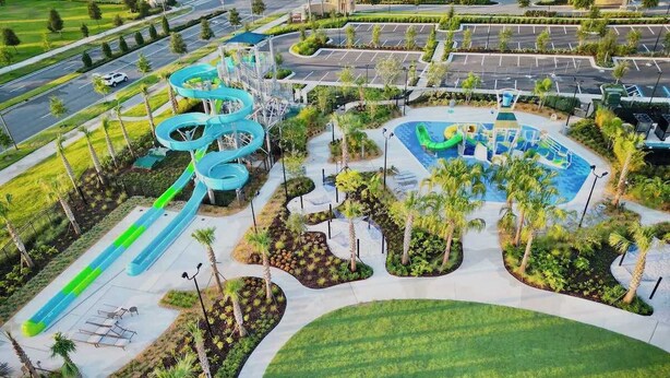 A water park with multiple slides and pools, surrounded by landscaped areas and palm trees.
