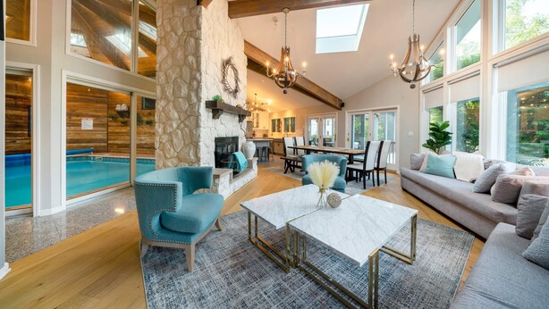 A spacious living area with a pool, stone wall, and modern furniture.