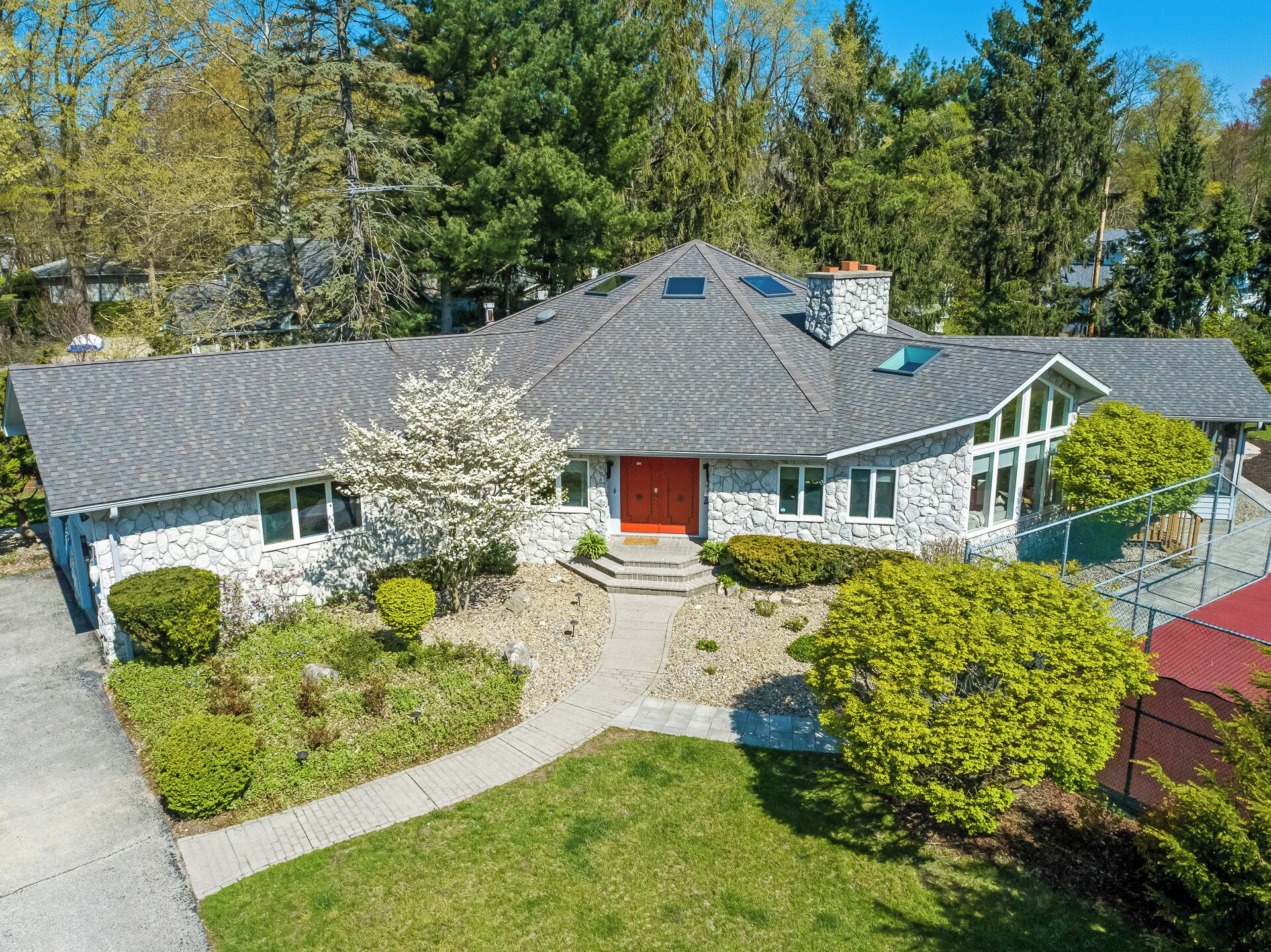 A stone house with a red door, a small porch, and a well-maintained lawn.