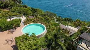 Ein Pool, umgeben von üppiger Vegetation, mit Blick auf einen Strand und das Meer.