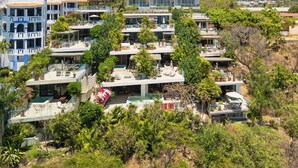 Ein mehrstöckiges Hotel mit Balkonen, Außenbereich und üppiger Bepflanzung.