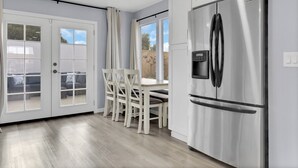 A modern kitchen with a stainless steel refrigerator, white cabinetry, and a dining area with a table and chairs. - Entire house near Monterey with Jacuzzi (Salinas)
