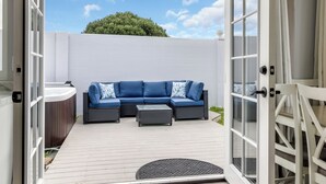An open patio with a blue sectional sofa, a small table, and a hot tub. - Entire house near Monterey with Jacuzzi (Salinas)