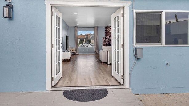 A hallway with a door leading to a room, a window on the right, and a light fixture on the wall. - Entire house near Monterey with Jacuzzi (Salinas)