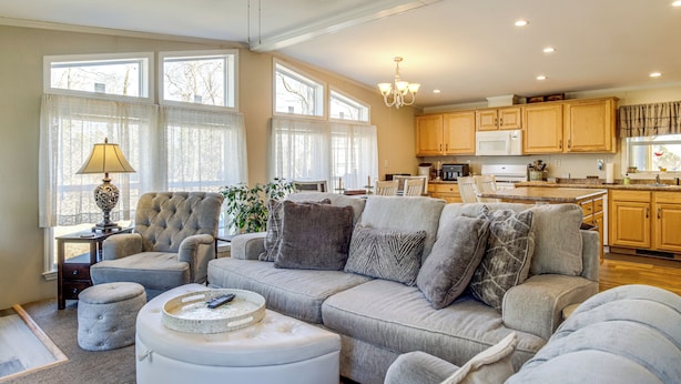 A spacious living room with a grey sofa, ottoman, and a ceiling fan. - 1 Mi to Boat Ramp: Peaceful Deal Island Home! (Deal Island Historic District)
